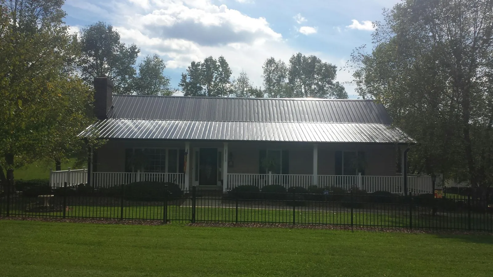 Gray metal roof on a brick ranch with a full width front porch — Gutter Guard Installation work by our crew in Beulah