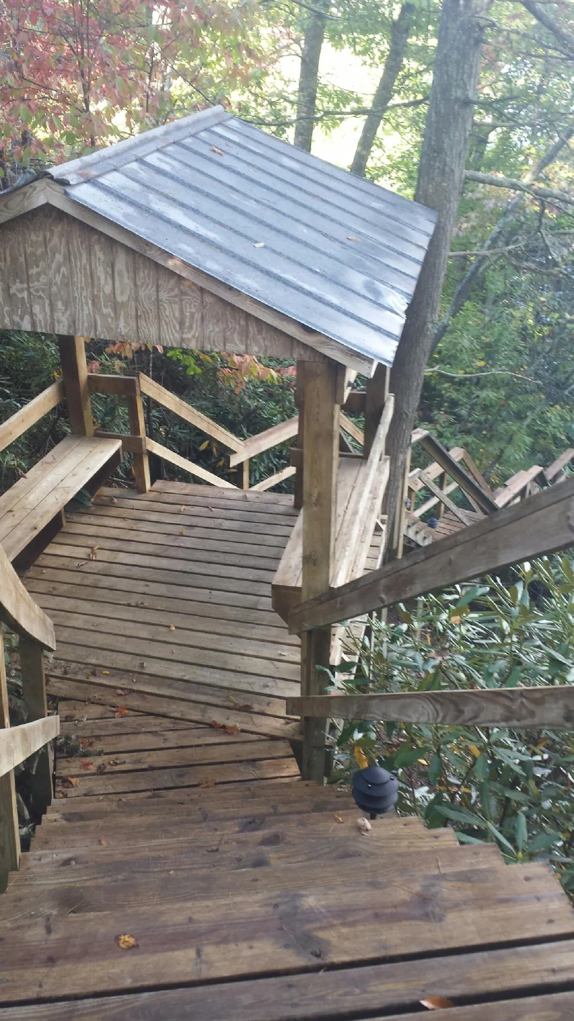 Metal roofed shelter over wooden steps on a wooded walkway — Skylight Repair & Installation work by our crew in Beulah