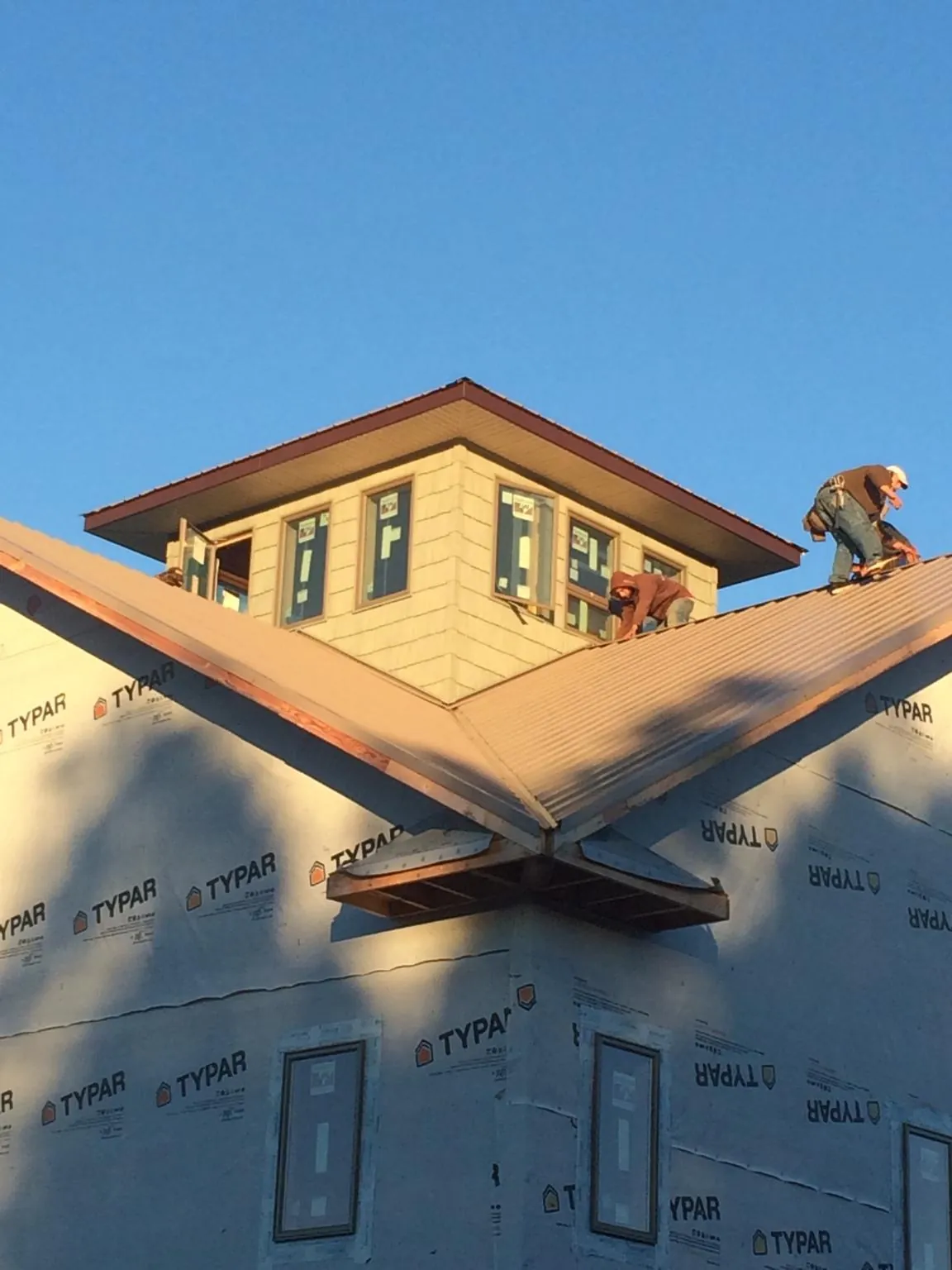 Roofers working around a rooftop cupola on a new metal roof at sunset — Roof Waterproofing in Beulah by Roofing Brothers